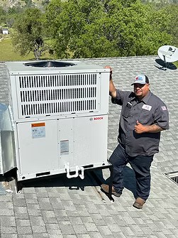 HVAC technician working on a rooftop unit in Fresno