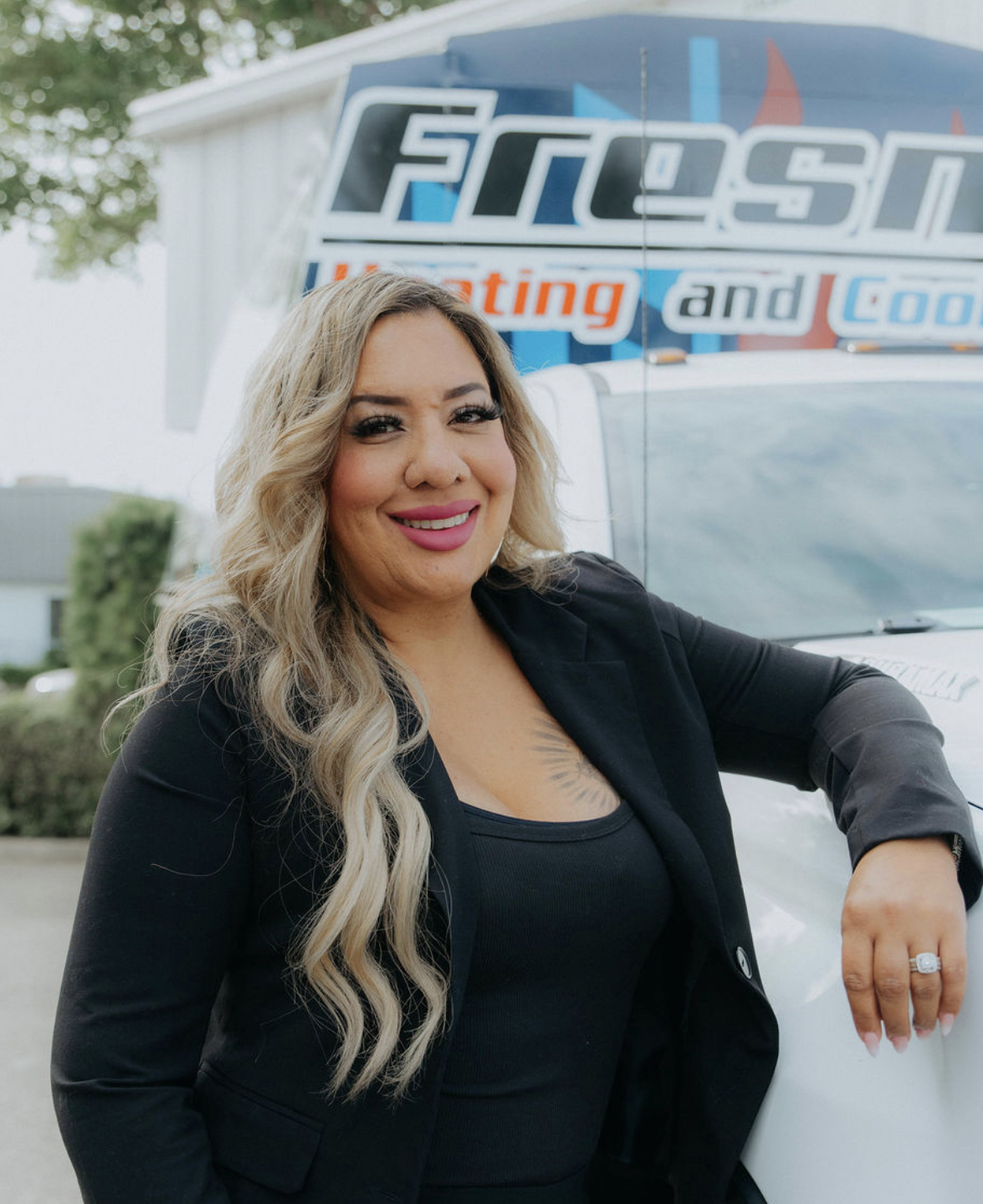Stephanie Larios, proud owner of Fresno Heating and Cooling, smiling in front of a company service truck