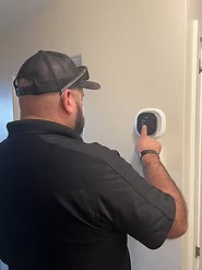 Technician adjusting a wall-mounted smart thermostat