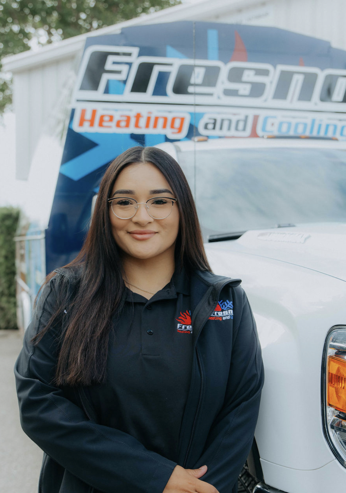 Jazmin, CSR at Fresno Heating and Cooling, standing in front of a company service truck