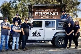 Fresno Heating and Cooling team standing in front of a vehicle near a Welcome to the City of Fresno sign