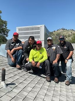 Group of Fresno Heating and Cooling technicians on a roof with an HVAC unit